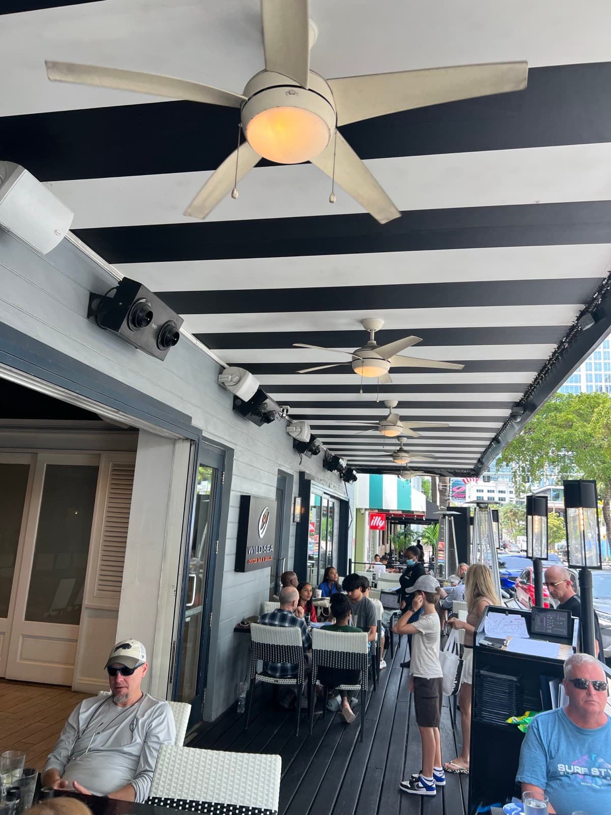 Wild Sea outdoor patio with mounted commercial TVs and patrons during service