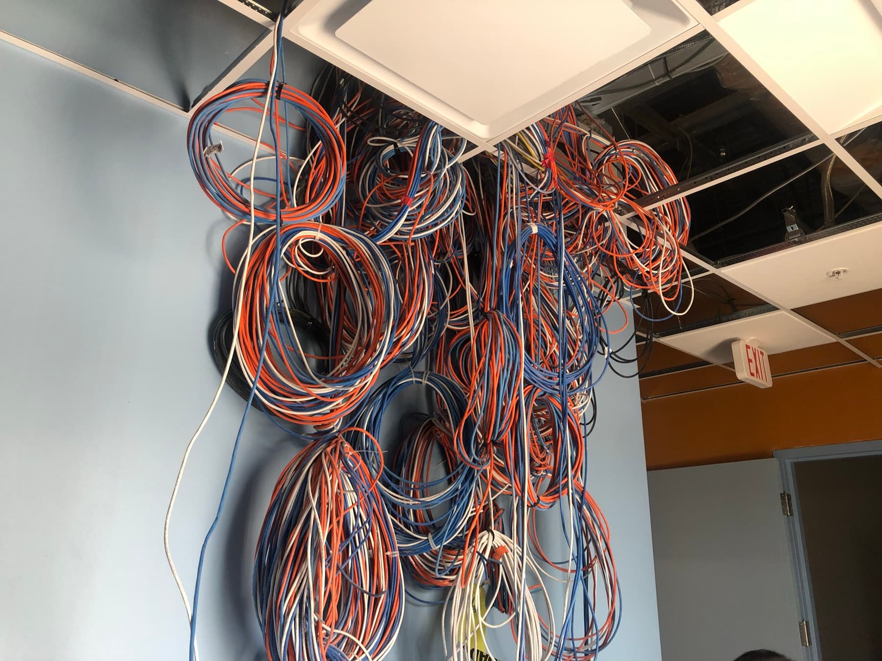 Hazardous tangled cables hanging from the ceiling left behind by a prior abandoned install