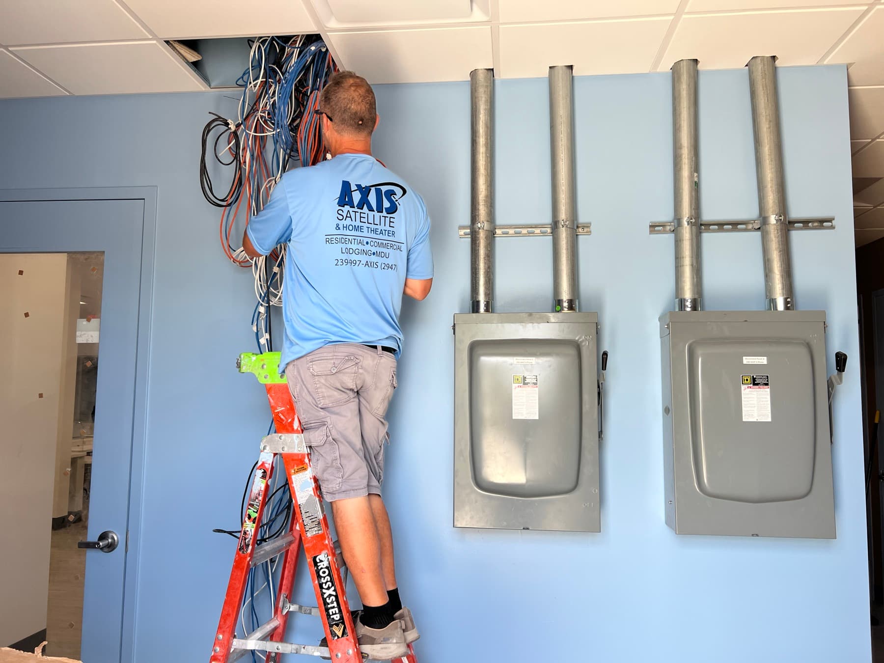 Axis technician working overhead to rebuild the structured cabling backbone