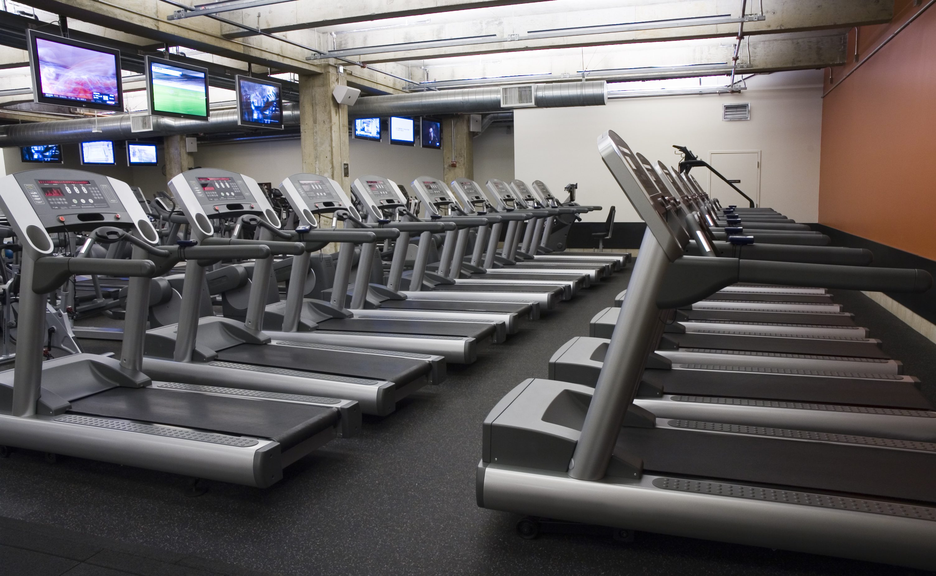 A row of treadmills in a spacious, well-lit gym.