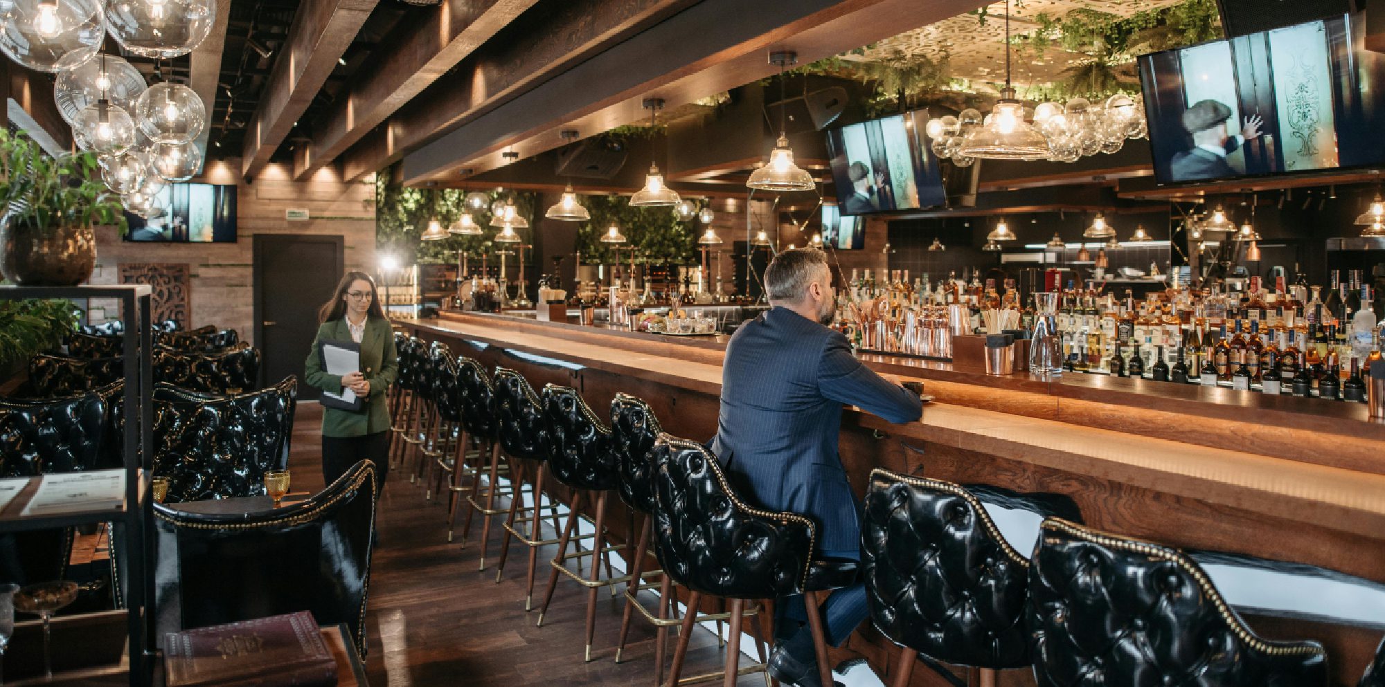 Man sitting alone at a dimly lit bar with a drink.